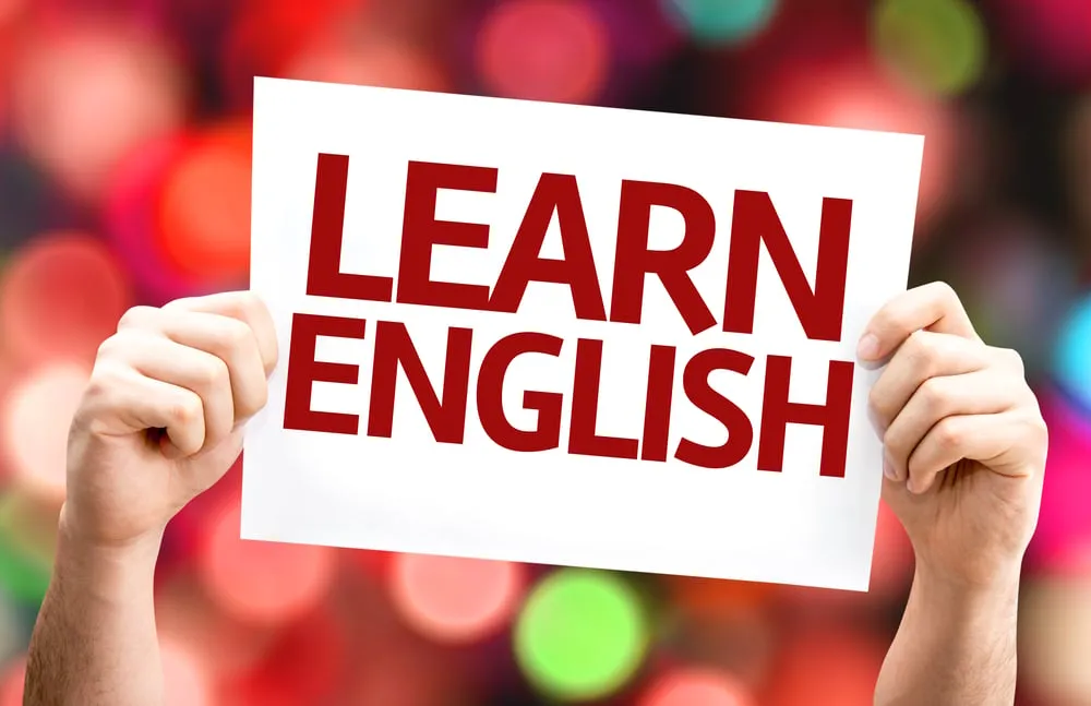 Hände halten ein Schild mit der Aufschrift Learn English vor bunten Lichtern
