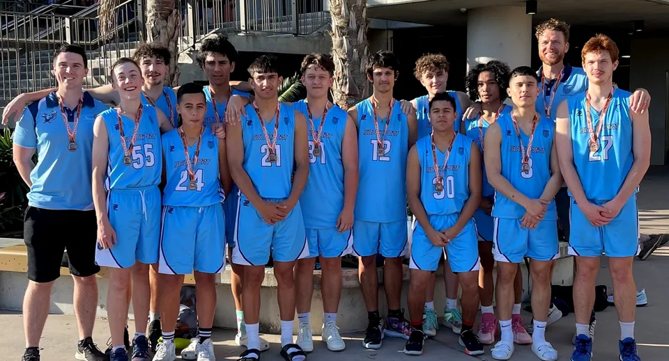 Un gruppo di ragazzi in divisa blu da basket si trova davanti all'edificio della Southport State High School.