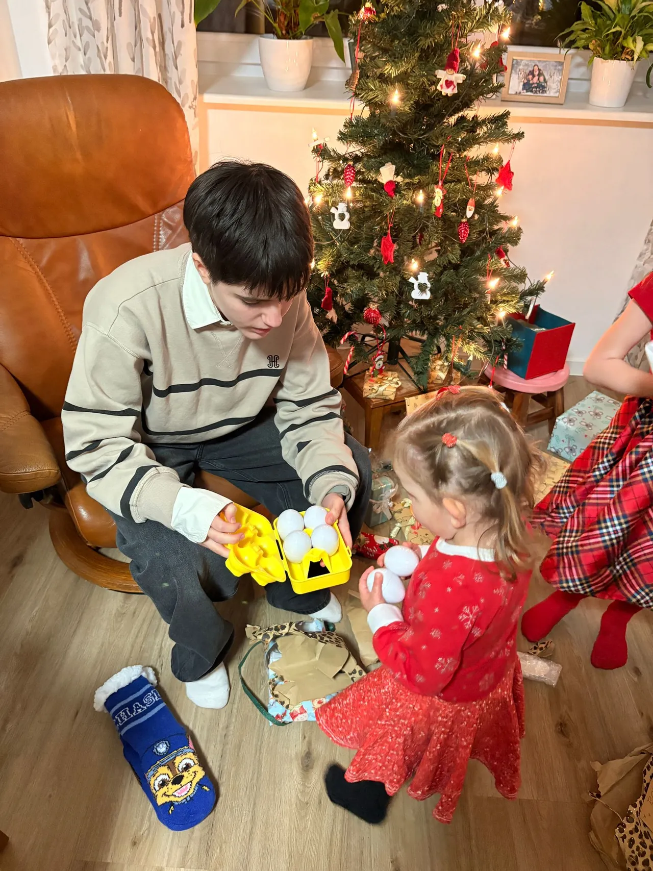 Ragazzo e bambina aprono i regali accanto all'albero di Natale