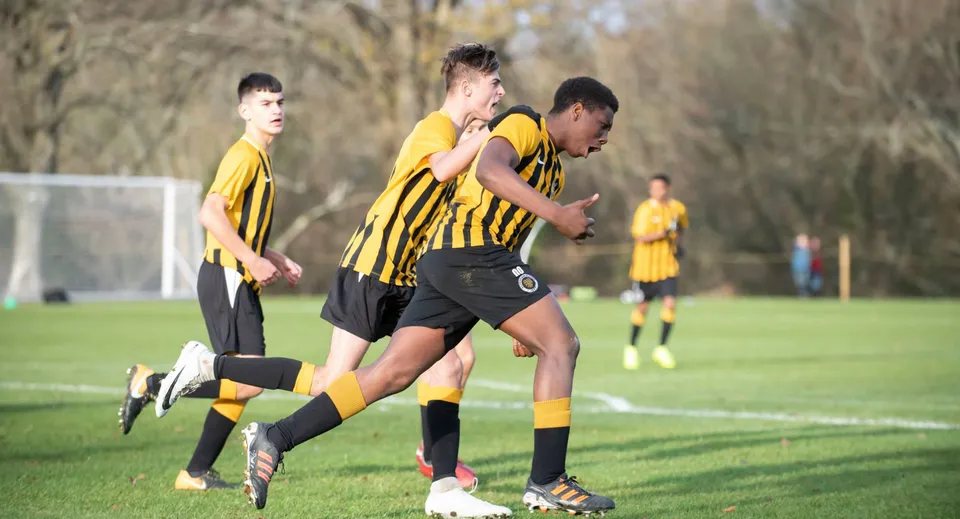 Studenti del De la Salle College Macroom giocano a calcio su un campo con una porta visibile.