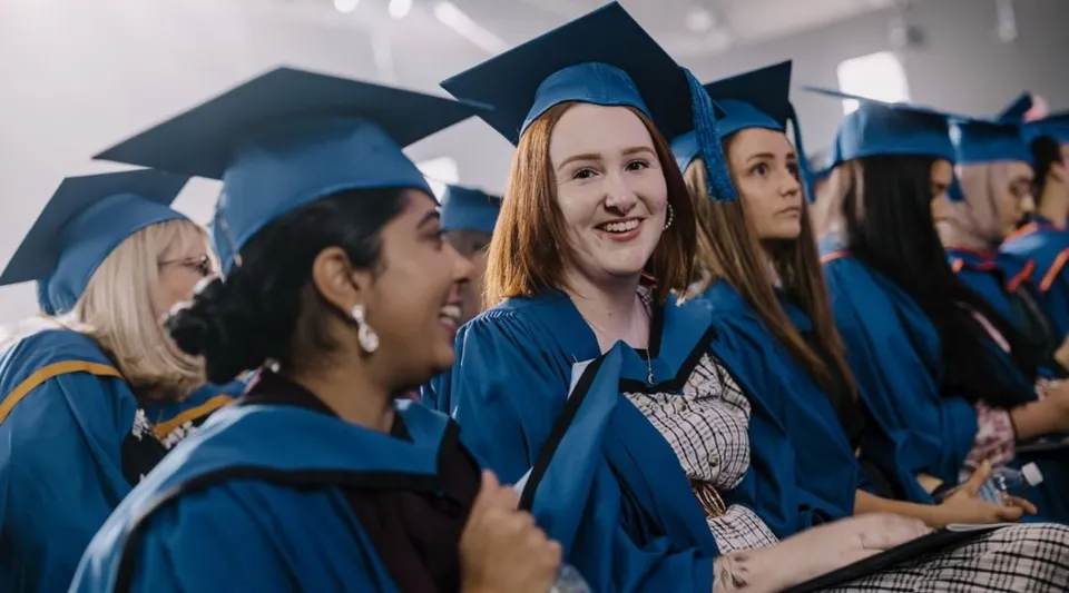 Un gruppo di laureati in toga blu si trova nel corridoio della Wollongong University.