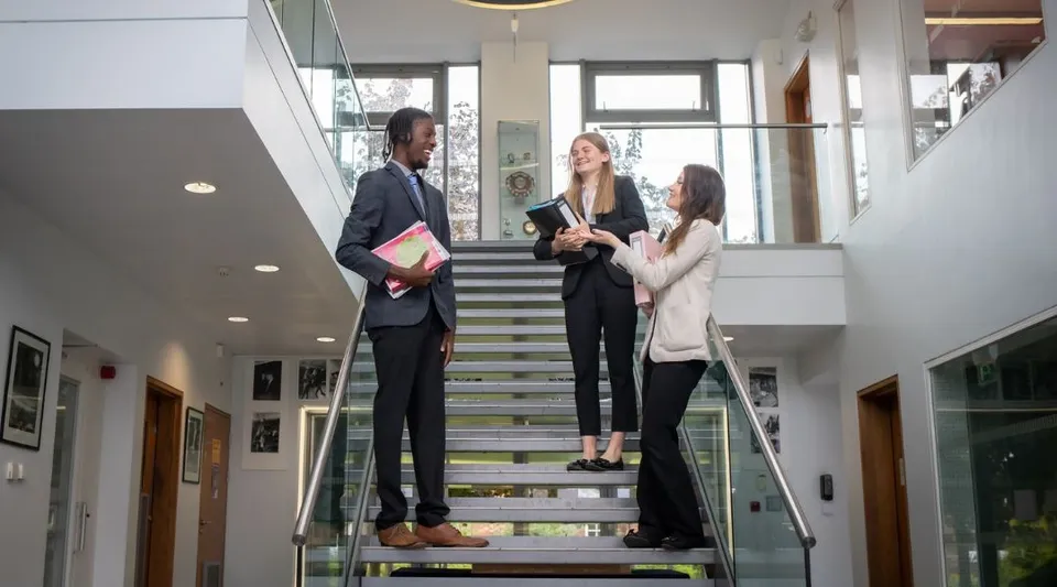 Tre persone si trovano su una scala in un edificio moderno del campus della St. Dominic's Grammar School.