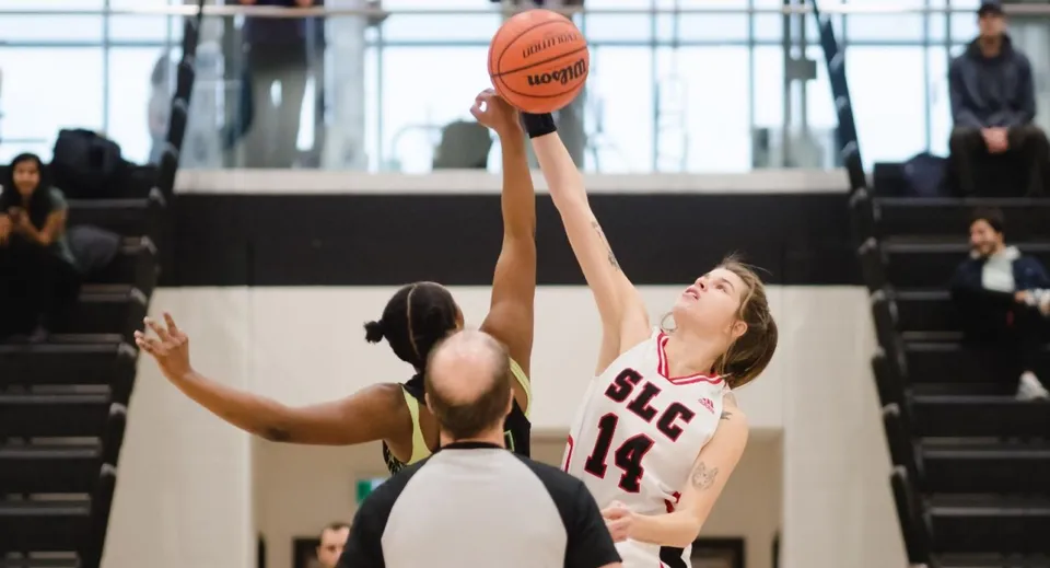 Un jugador de baloncesto con camiseta roja salta para lanzar durante el juego en el campus del St. Lawrence College.