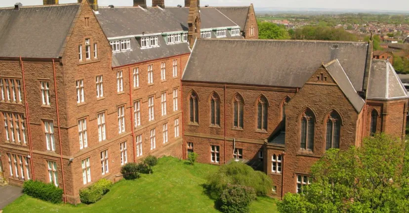 L'edificio della Austin Friars School con un paesaggio verde in primo piano e la città sullo sfondo.