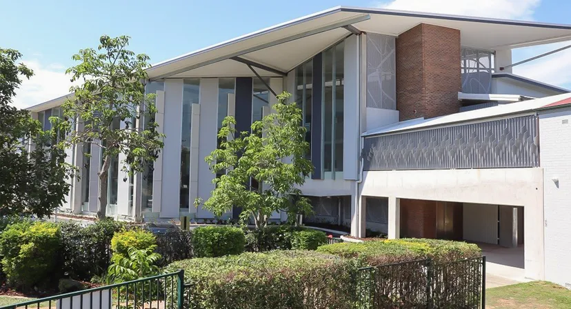 L'edificio moderno a più piani con ampie finestre e balcone nel campus della The Gap State High School è circondato da una rigogliosa vegetazione.