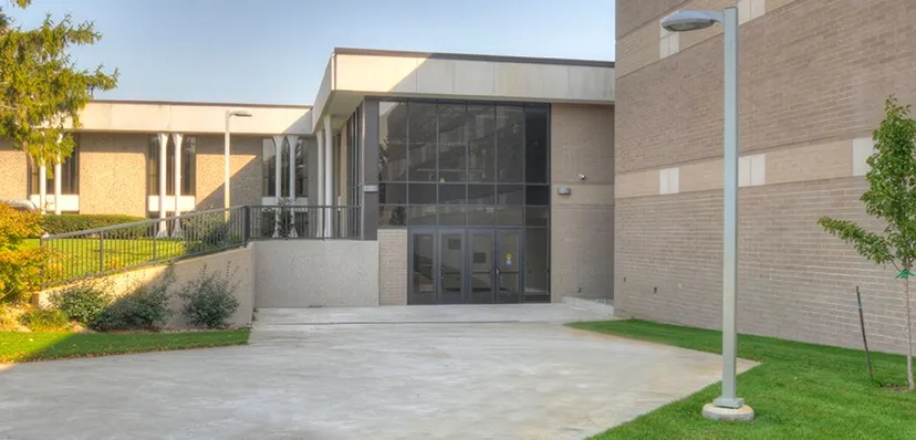 L'edificio moderno della Western Michigan Christian School con facciata in vetro e un ingresso pavimentato sotto un cielo limpido.