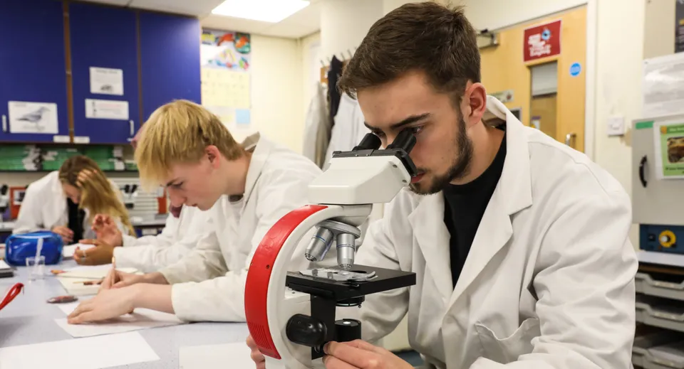 Uno studente della scuola Embley guarda attraverso un microscopio nel laboratorio di scienze.
