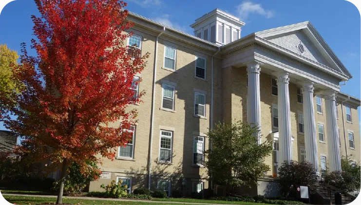 Wayland Academy: Schulgebäude mit Säulenportal und herbstlich gefärbtem Baum