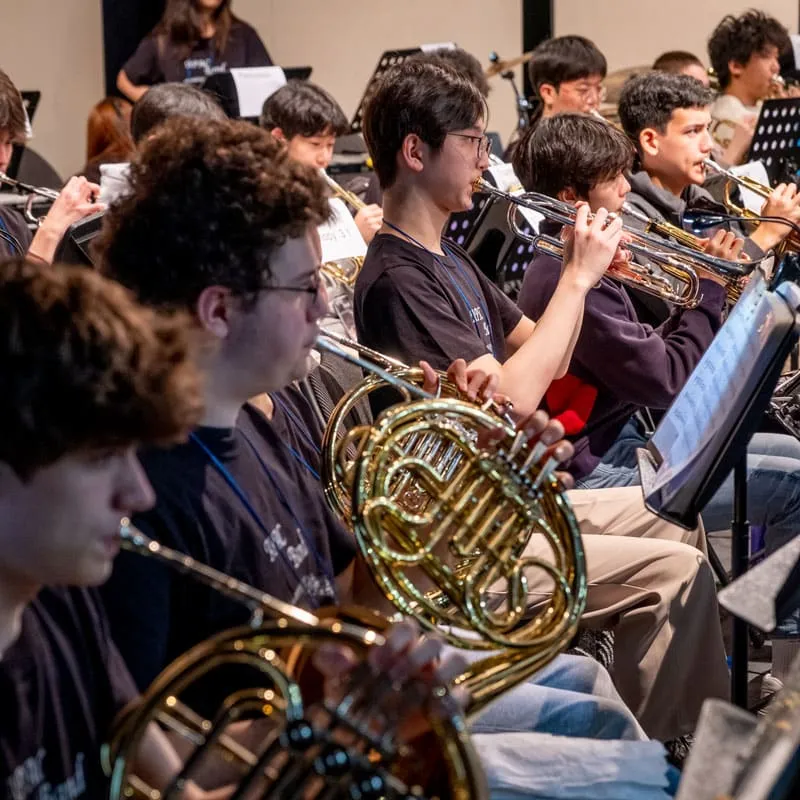 Eine Gruppe von Musikschülern der Taejon Christian International School spielt Blechblasinstrumente in Uniform.