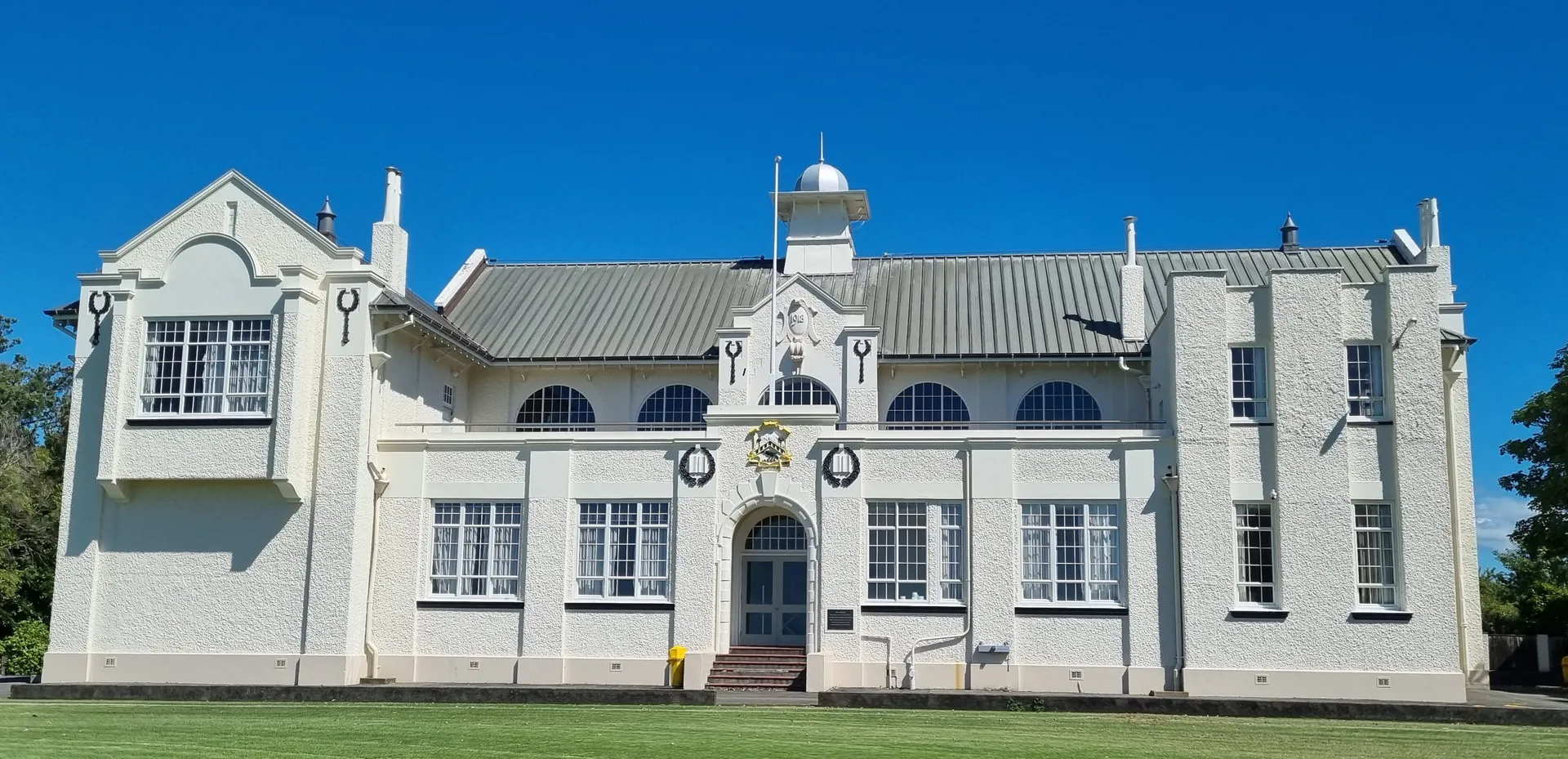 L'imponente edificio principale della New Plymouth Boys' High School si trova sotto un cielo azzurro terso e su un prato ben curato.