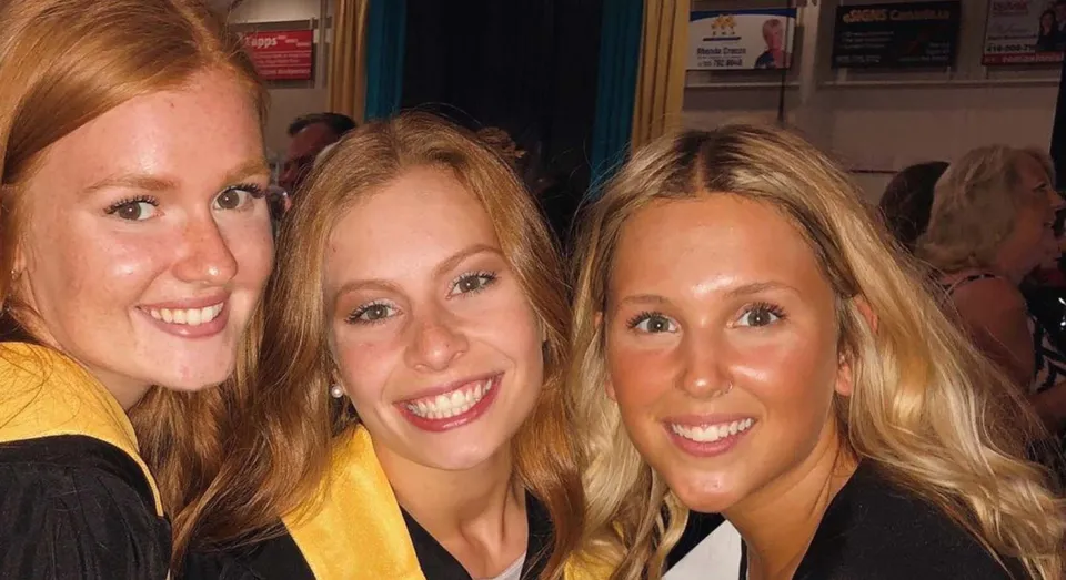Tre studentesse sorridenti con i capelli biondi alla Nantyr Shores Secondary School in un'area pubblica.
