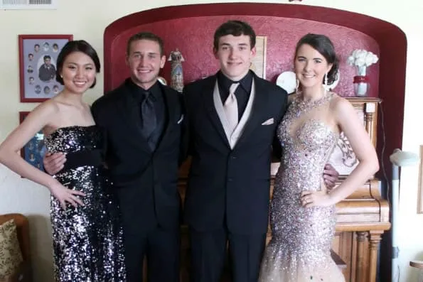 Cuatro jóvenes vestidos de gala posan sonrientes en el interior de una casa