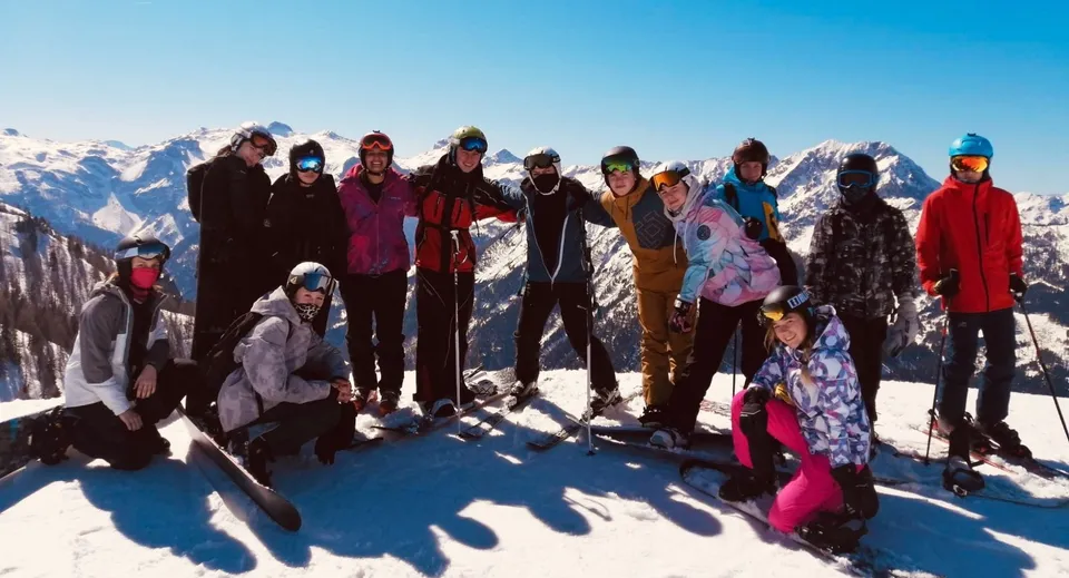 Un gruppo di studenti della RGS Surrey Hills posa in abiti invernali su un pendio innevato con uno sfondo montano.