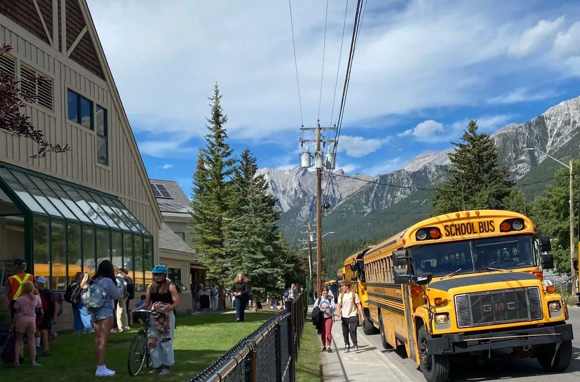Scuolabus giallo davanti alla Canmore Collegiate High School, sullo sfondo le Montagne Rocciose