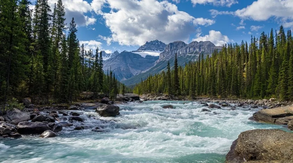 Un torrente di montagna scorre attraverso una valle boscosa con cime innevate sullo sfondo nel territorio della Marymount Academy.