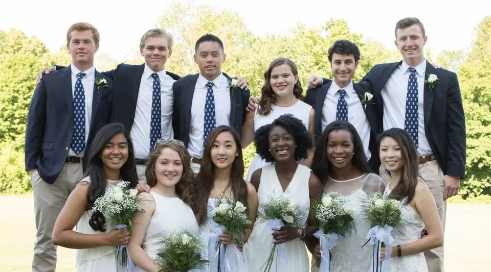 Un gruppo di studenti della Canterbury School è all'aperto davanti agli alberi, in abito formale e con dei fiori.