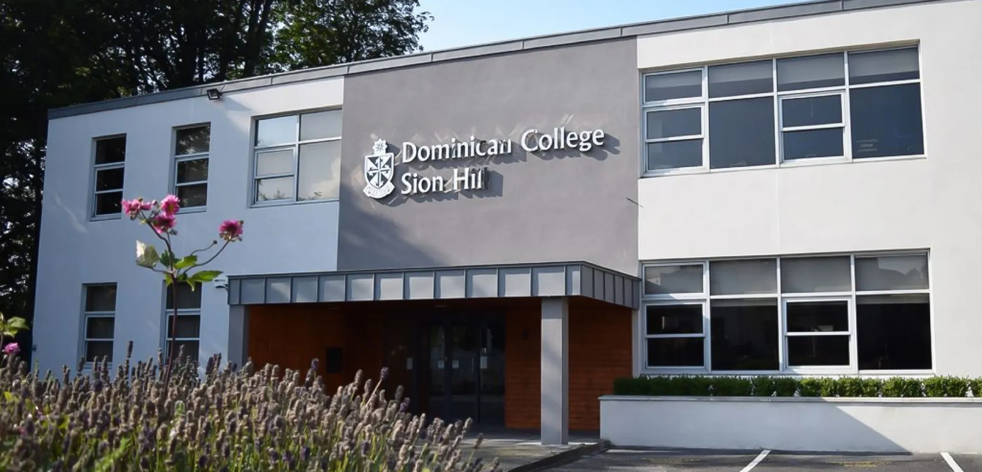 L'edificio scolastico del Dominican College Sion Hill con il logo della scuola sulla facciata grigia e bianca.