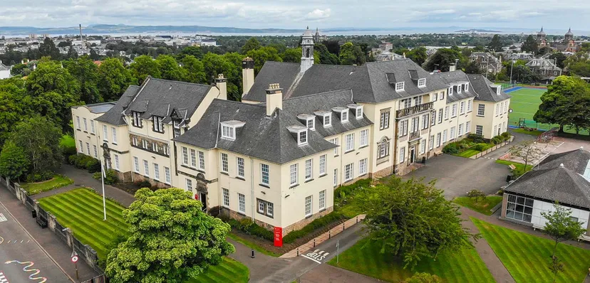 L'edificio principale storico della St. George's School a Edinburgh circondato da alberi con vista sulla città.