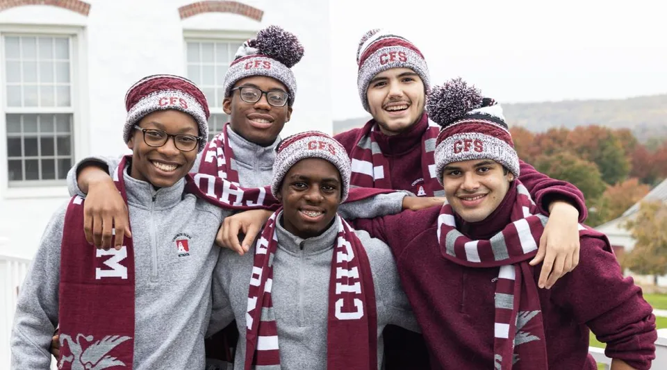 Un gruppo di studenti della Church Farm School indossa abbigliamento invernale uniforme e si trova davanti a un edificio con colonne.