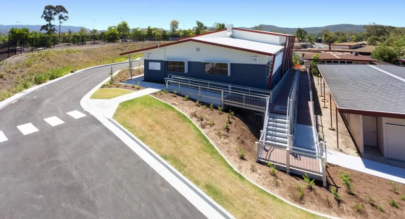 L'edificio moderno a due piani della Nerang State High School sorge su una collina erbosa con le montagne sullo sfondo.