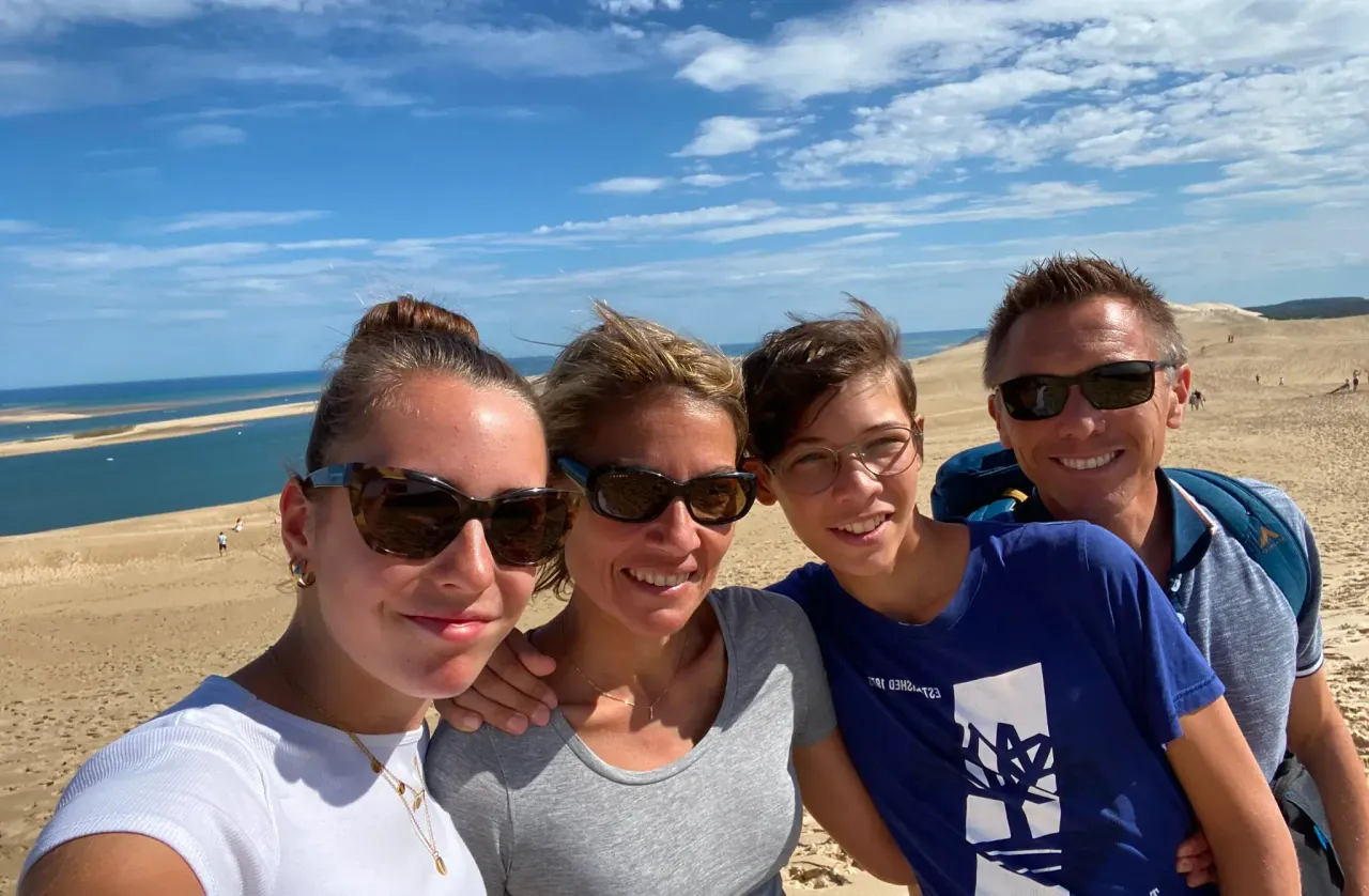 Selfie di famiglia su una grande duna di sabbia con il mare sullo sfondo