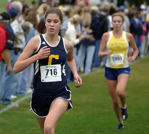 Una corredora de Clarkston High School compite en una carrera de campo a través sobre hierba.