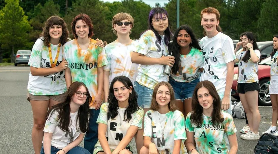 Un gruppo di studenti e studentesse si trova insieme all'aperto nel campus del Hopkinton Public School District.