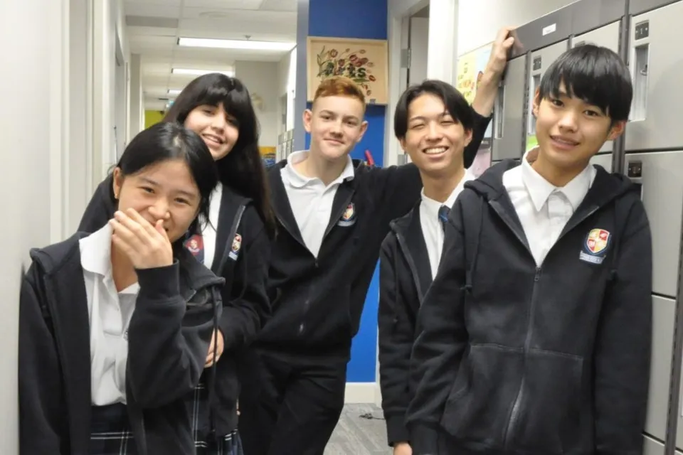 Un gruppo di studenti in divisa scolastica si trova nel corridoio della Pattison High School davanti a diverse decorazioni scolastiche.
