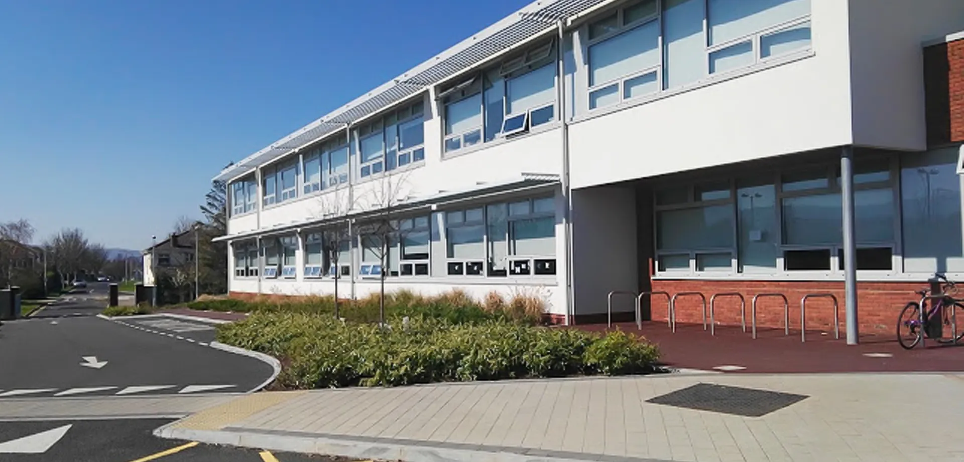 L'edificio moderno a più piani del Sancta Maria College Ballyroan con ampie finestre e un camminamento pavimentato in primo piano.