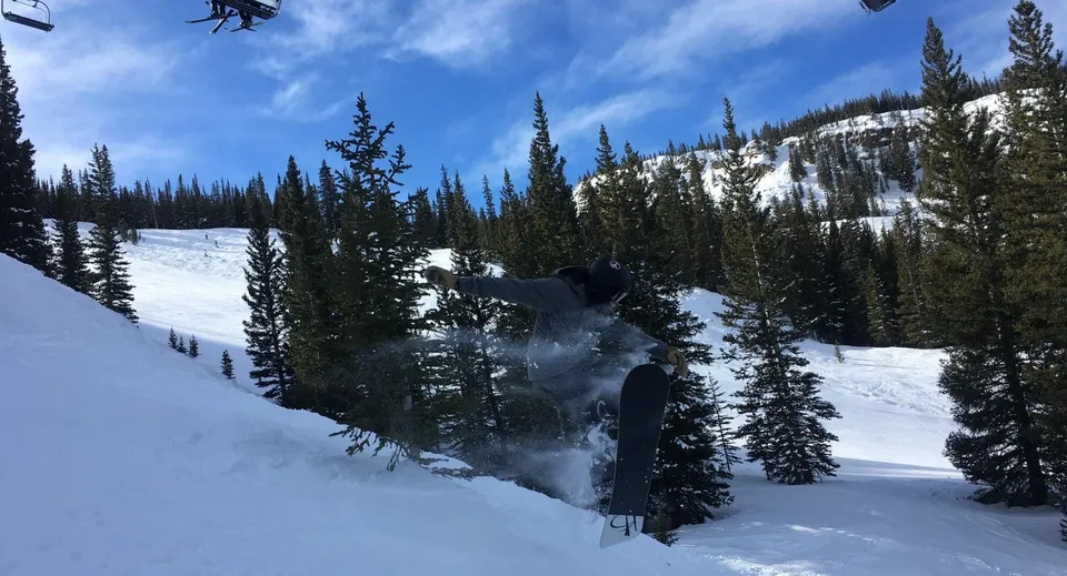Uno sciatore scia sulla neve davanti a un paesaggio montano invernale nel terreno della Colorado Rocky Mountain School.