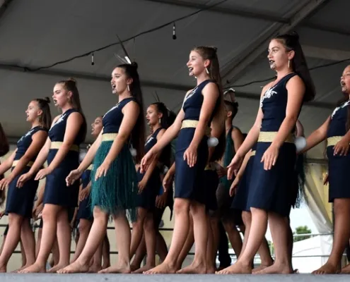 Estudiantes de la Waiheke High School realizan descalzas una presentación tradicional maorí sobre un escenario.
