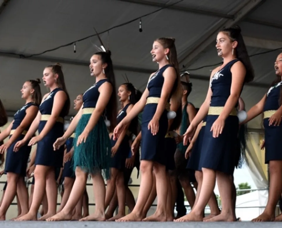 Studentesse della Waiheke High School eseguono a piedi nudi una performance tradizionale maori su un palco.