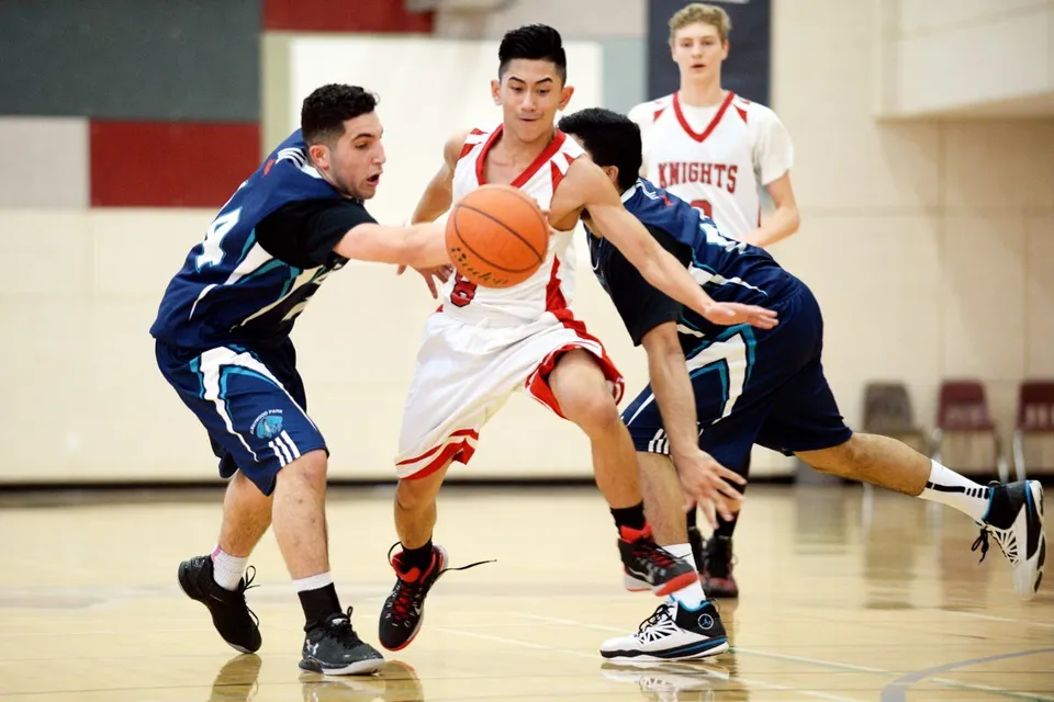 Due studenti giocano a basket in una partita sul campo sportivo della Prince George Secondary School.