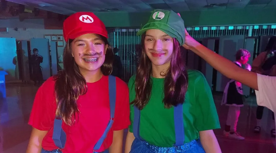 Due studentesse della Carrefour de l’Acadie indossano costumi colorati e si mettono in posa durante una festa di Carnevale nell'edificio scolastico.