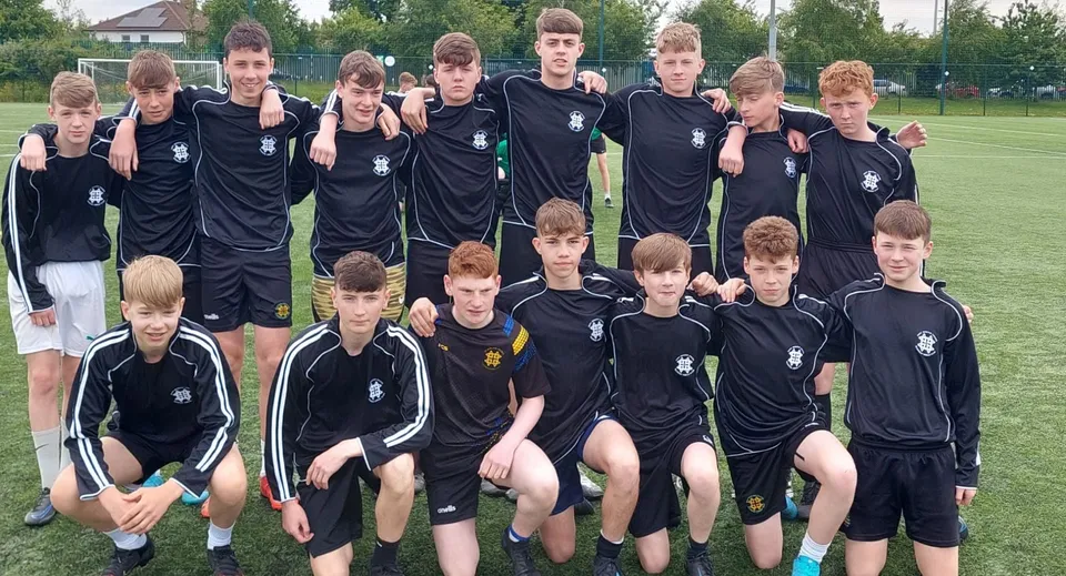 Un gruppo di giovani calciatori con maglie nere sul campo sportivo del St. Benildus College.