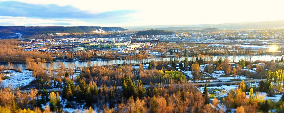 Foto aerea che mostra la città con montagne innevate e un lago con vegetazione autunnale vicino alla College Heights Secondary School.