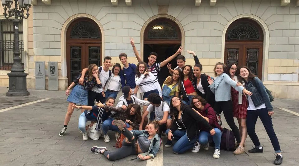 Un gruppo di studentesse posa davanti a un edificio decorato con volte nel campus del Lycée Jean Brito.