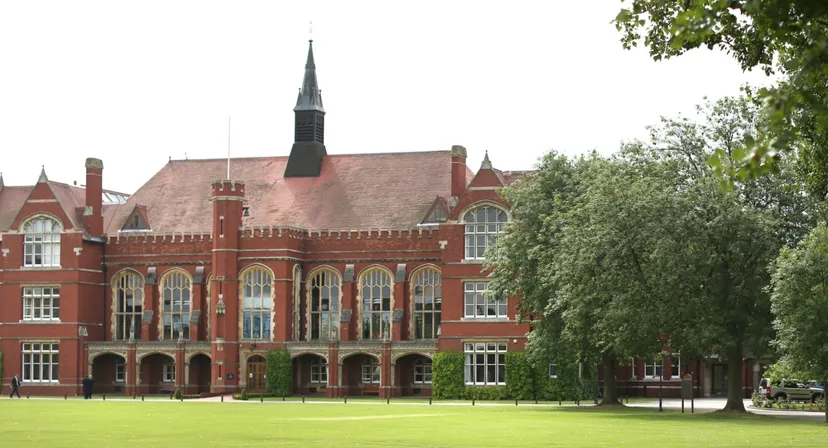 L'edificio storico in mattoni con un'alta torre nel campus della Bedford School è circondato da alberi.