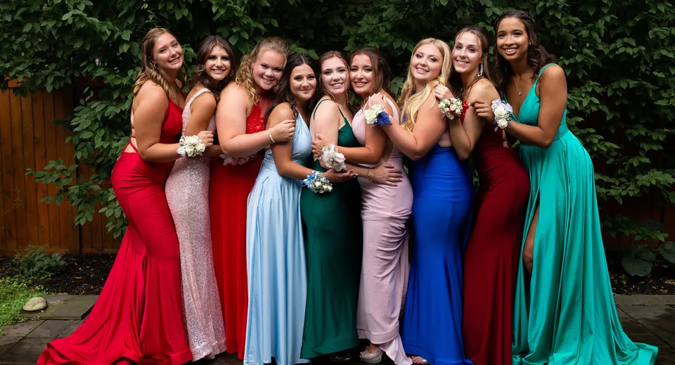 Un gruppo di giovani studentesse della Ballingarry Presentation School all'aperto su un prato verde con abiti eleganti e colorati.