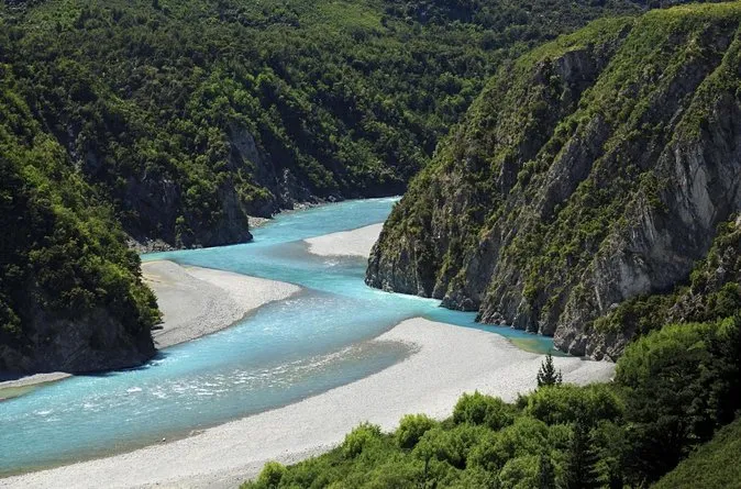 Un río turquesa serpentea a través de un desfiladero boscoso con rocas cubiertas de musgo cerca de la Christchurch Boys High School.