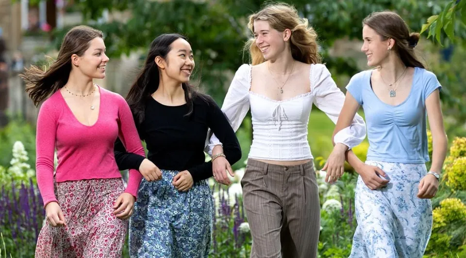 Quattro studentesse di diversa origine camminano insieme su un viale alberato nel campus della St. Mary’s Calne.