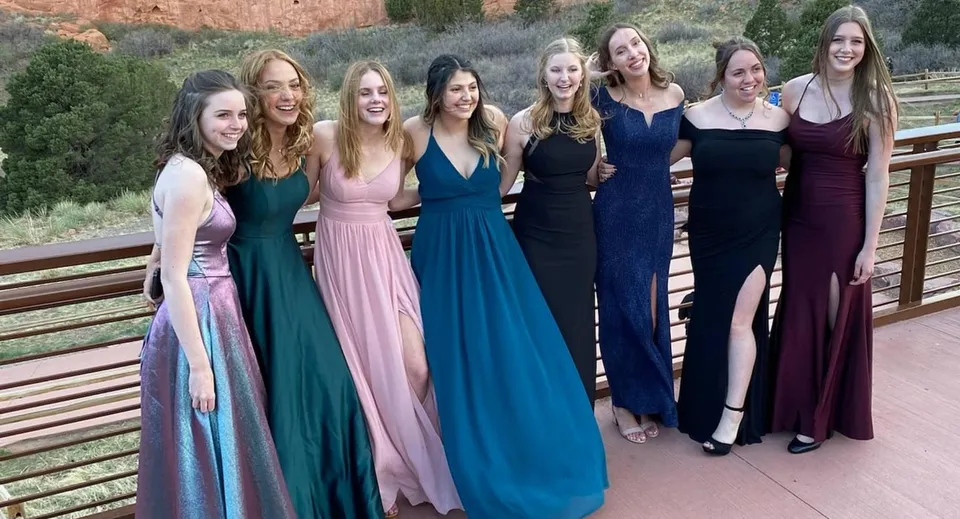 Un gruppo di studentesse della Earl Marriott Secondary School si trova su una terrazza in legno davanti a un paesaggio naturale.