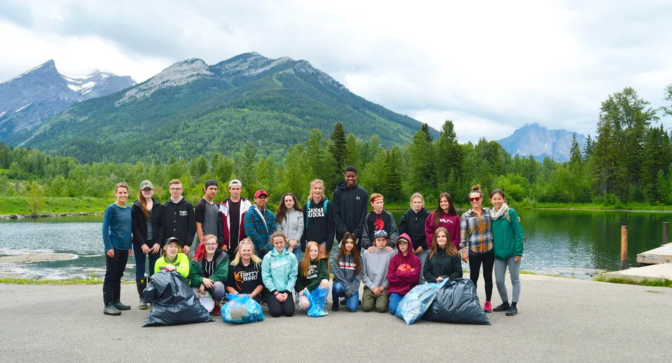 Gli studenti della Fernie Secondary School posano con sacchi della spazzatura davanti a un lago e alle montagne.