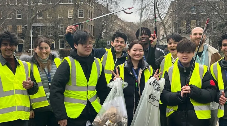 Studenti della Guildhouse School London sono in piedi insieme con gilet di sicurezza nell'area urbana.