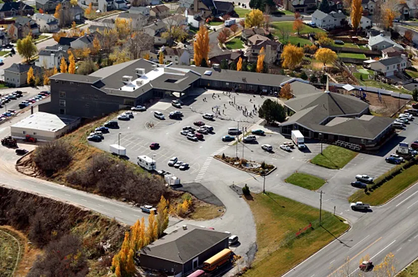 L'edificio principale a più piani della Layton Christian Academy con un grande piazzale esterno e piccoli edifici circostanti davanti a un paesaggio collinare.