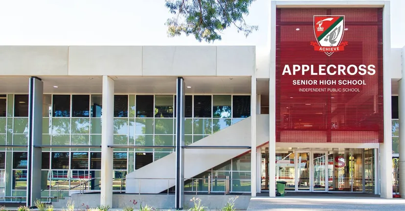 L'edificio della Applecross Senior High School con una grande insegna rossa è circondato da alberi e aree verdi.