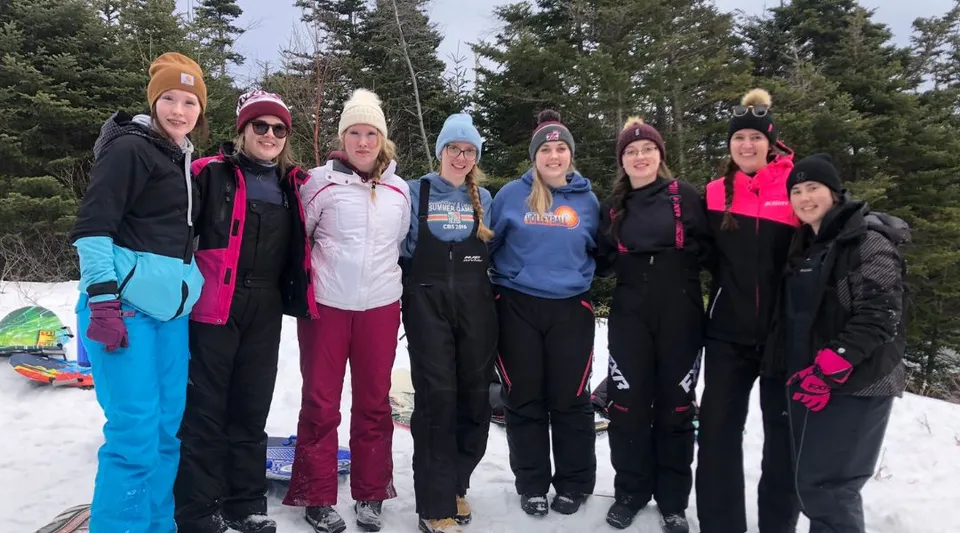 Un gruppo di studenti della Mobile Central High in abbigliamento invernale si trova in un bosco innevato.