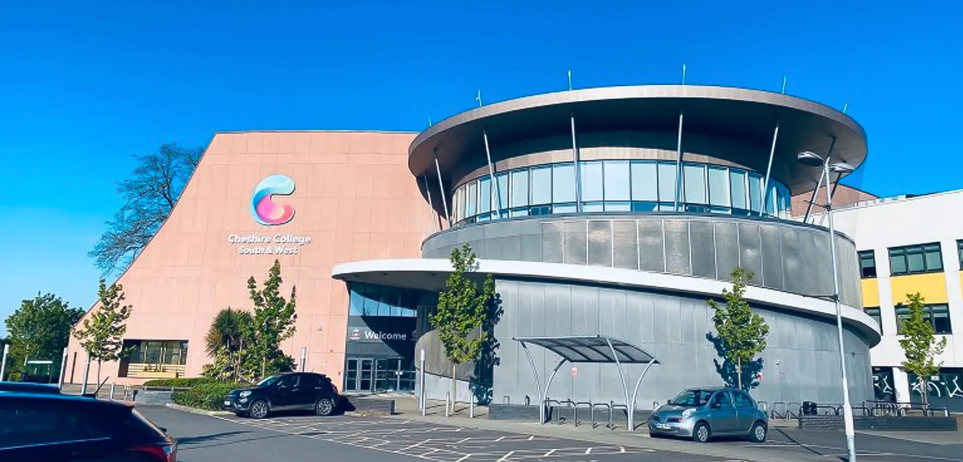 L'edificio moderno del Cheshire College South & West con un elemento circolare e il logo sulla facciata.