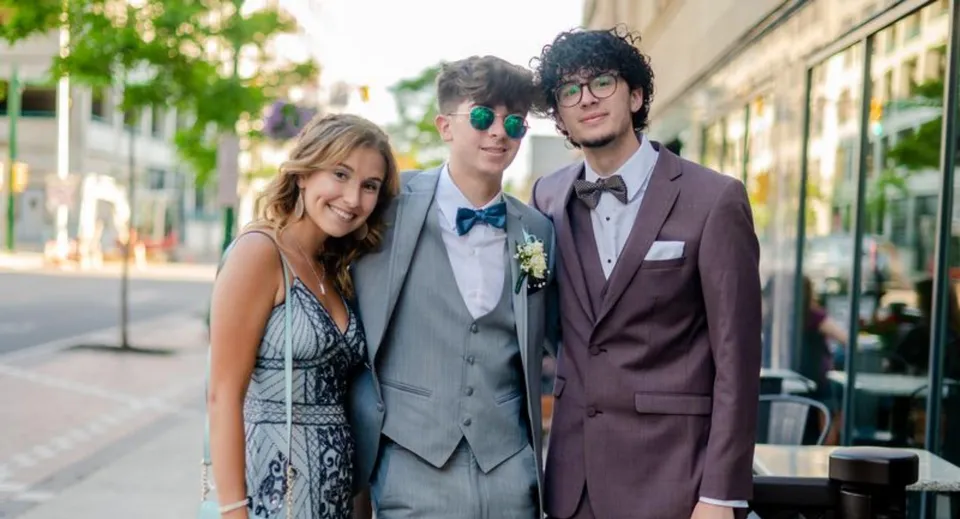 Tre studenti della Mountainview High School sono insieme su una strada in città con aree verdi ed edifici sullo sfondo.
