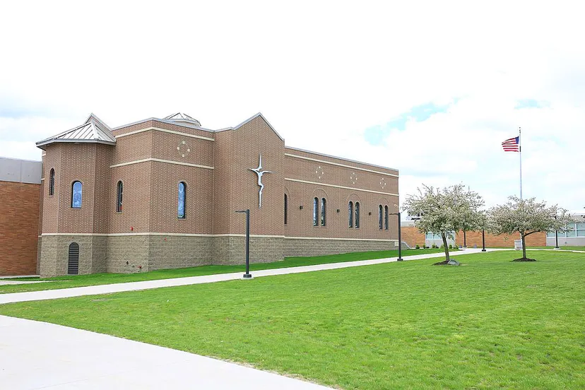 L'edificio in mattoni della Lansing Catholic High School con una croce sulla facciata e un prato verde in primo piano.